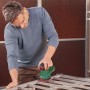 Mann schleift Metallrahmen mit Bosch Akku-Multischleifer UniversalSander 18V-10. Kompakte Schleifmaschine für präzise Arbeiten.