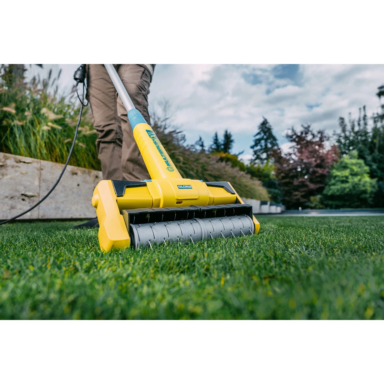Gloria MultiBrush XL Elektro-Oberflächenbürste im Einsatz auf Rasen. Gartenhandgerät mit rotierender Bürste.