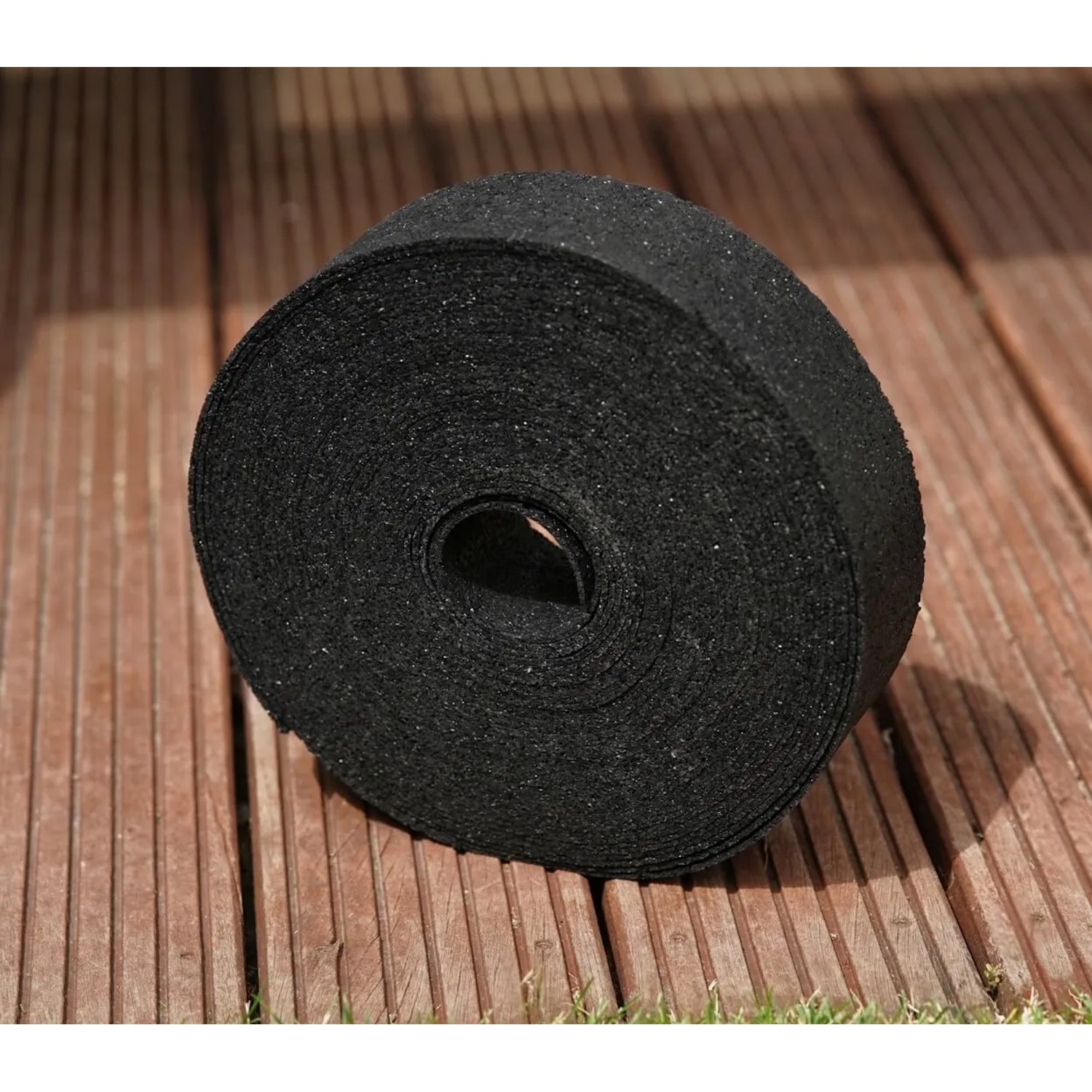 Schwarze Bauheld Terrassenpads Rolle aus Gummigranulat auf Holzterrasse. Trittschalldämmung für Außenbereich.