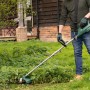 Mann trimmt Wildwuchs mit grünem Bosch Elektro-Rasentrimmer AFS 23-37 im Garten. Leistungsstarker Trimmer für Rasenpflege.