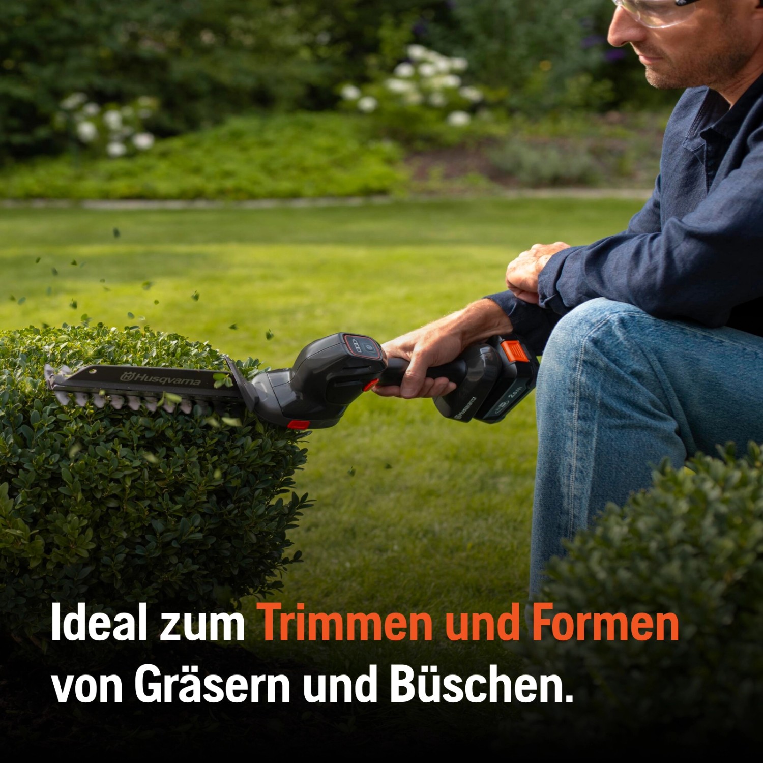 Husqvarna Akku-Grasschere Aspire S20-P4A im Einsatz beim Trimmen eines Busches.