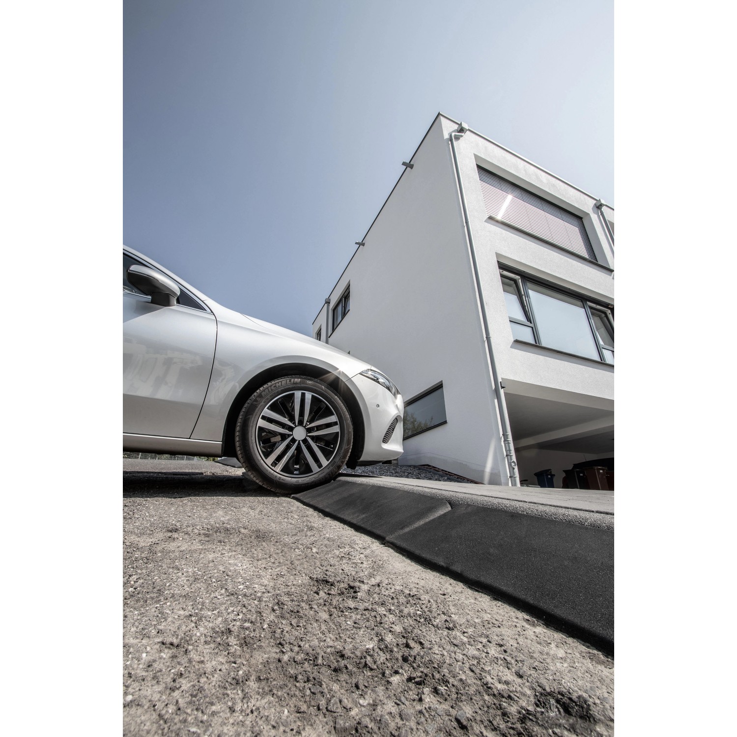 Terrasoft Bordsteinrampe XL im Einsatz: Auto fährt über Rampe auf Bordstein. Baugerät für leichteres Auffahren.