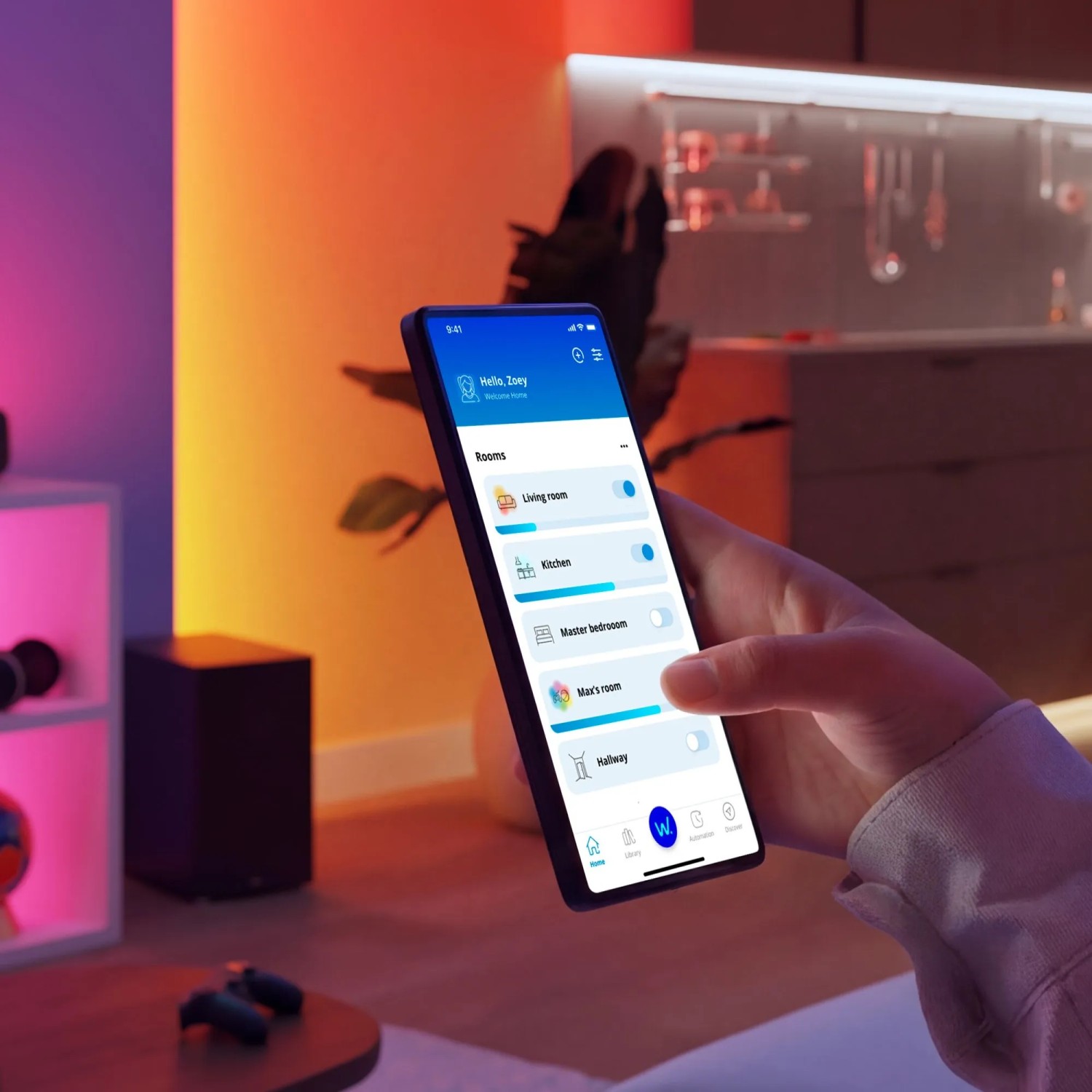 Hand steuert Philips Smart-LED-Tischleuchte über WiZ App auf Smartphone. Bunte Wall-Washing-Effekte schaffen Ambientebeleuchtung.