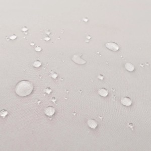 Wassertropfen perlen auf grauem, wasserabweisendem Stoffkissen der Garten-Garnitur ab.