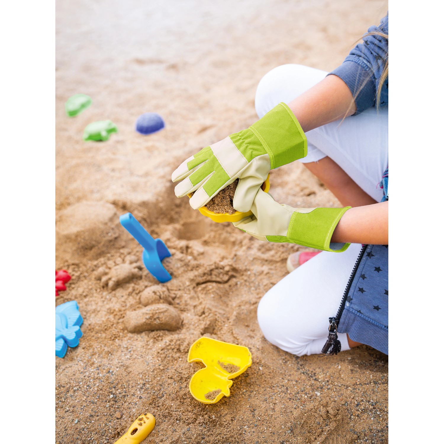 Kind spielt im Sandkasten mit gelben Kinderhandschuhen (Größe 4) der Kategorie Gartenbekleidung.
