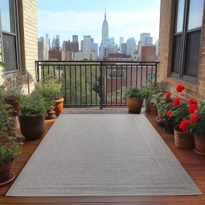 Grauer Ayyildiz Outdoor-Teppich Desert (140x200 cm) auf einem Balkon mit Pflanzen.