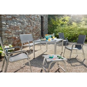 Gartentisch-Set: TischCUBICsil/ant mit Stühlen auf Kiesboden vor Steinwand.