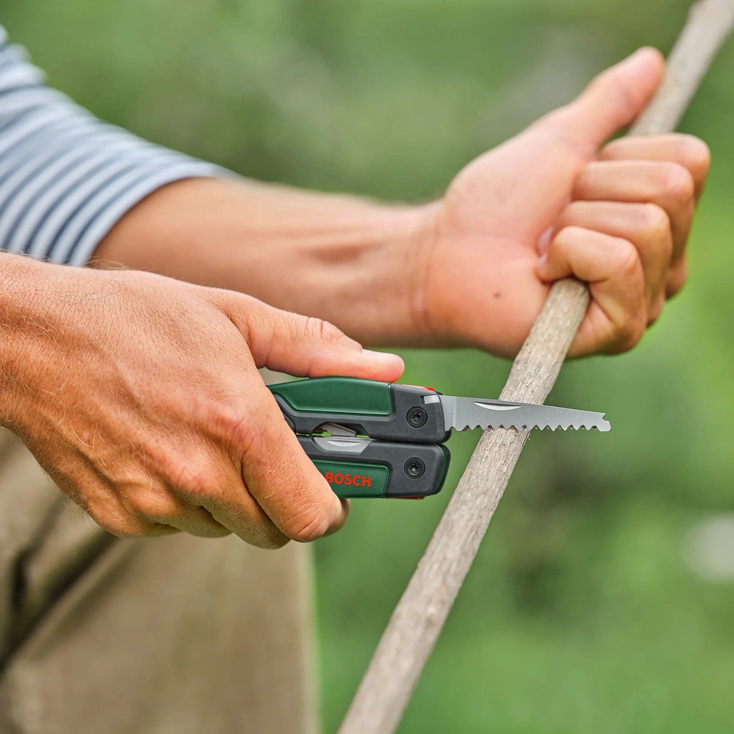 Bosch Multiwerkzeug 16-in-1 im Einsatz: Mann sägt Ast mit dem Multifunktionswerkzeug.