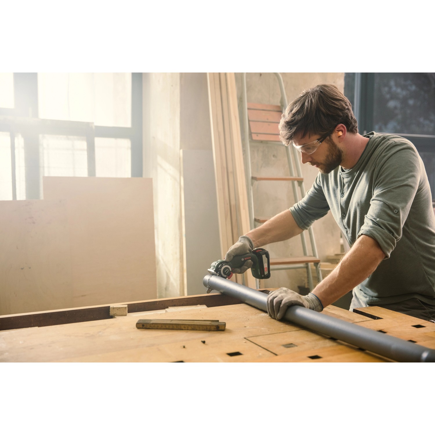 Mann sägt Rohr mit Bosch Akku-Säge NanoBlade AdvancedCut 18. Stichsäge für präzise Schnitte.
