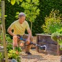Mann reinigt Holzkasten mit Gardena Akku-Multi-Reiniger AquaBrush. Inkl. Bürstenaufsatz.