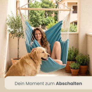 Frau entspannt im pazifik-blauen AMANKA Hängesessel auf Balkon mit Golden Retriever. Gemütlicher Baumwoll-Schwebesessel.