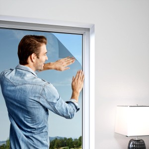 Mann bringt Windhager Pollenschutz-Set in Anthrazit an Fenster an.