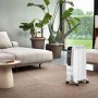 Weißer De'Longhi Dragon 5 Radiator im Wohnraum. Elektrisches Heizgerät mit Rollen.