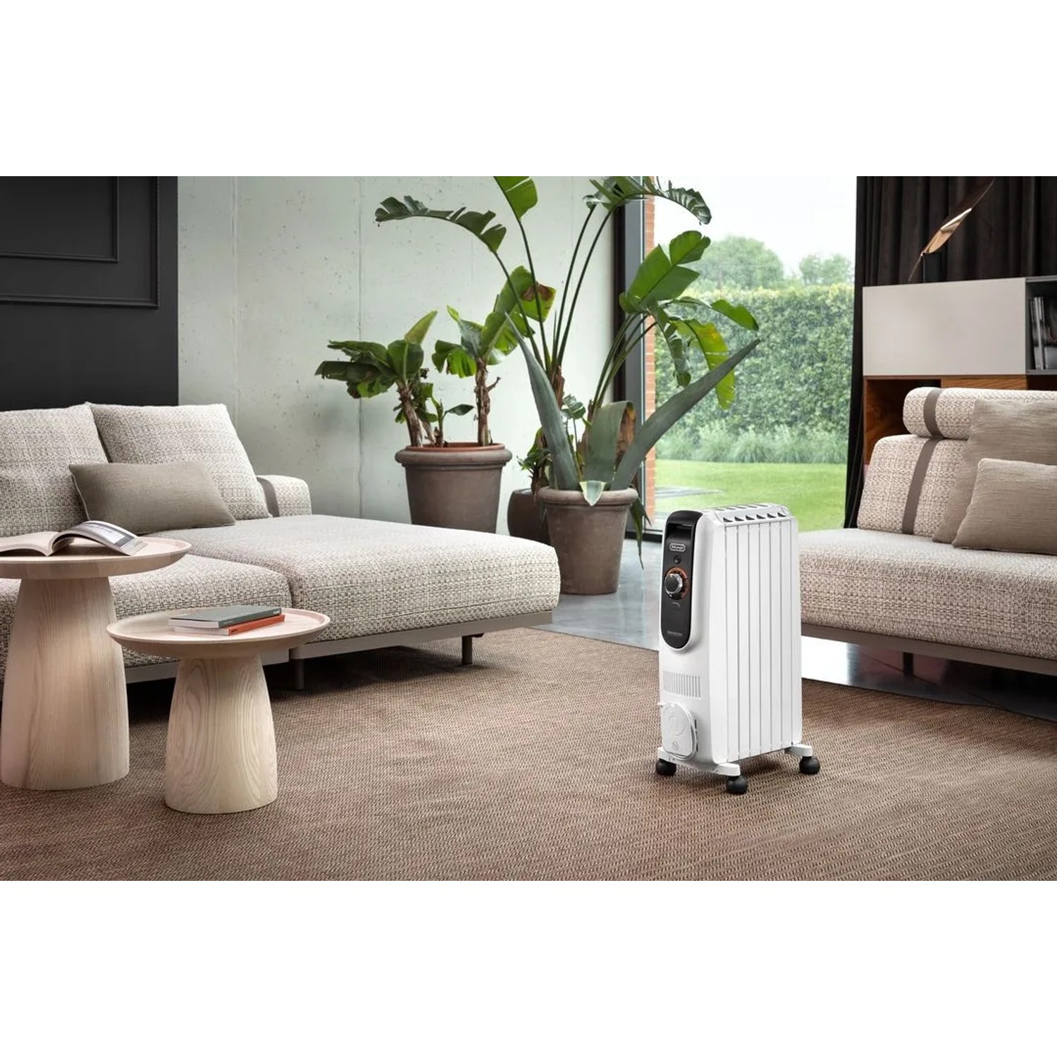 Weißer De'Longhi Dragon 5 Radiator im Wohnraum. Elektrisches Heizgerät mit Rollen.