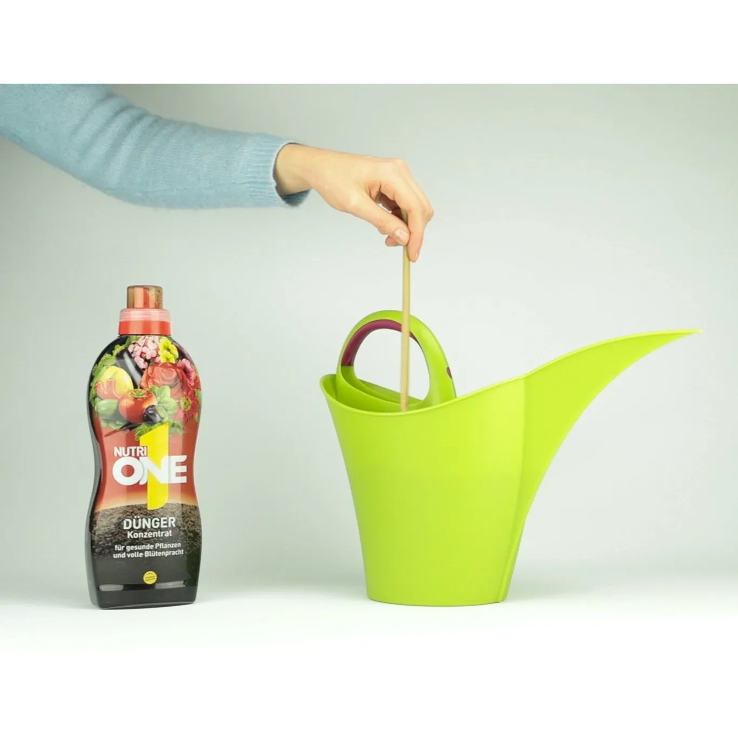Nutri One Universal-Dünger Flüssigkonzentrat neben grüner Gießkanne bei der Anwendung.