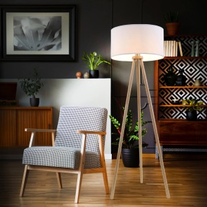 Brilo Stehleuchte mit weißem Stoffschirm und Holzfüßen im Wohnzimmer.