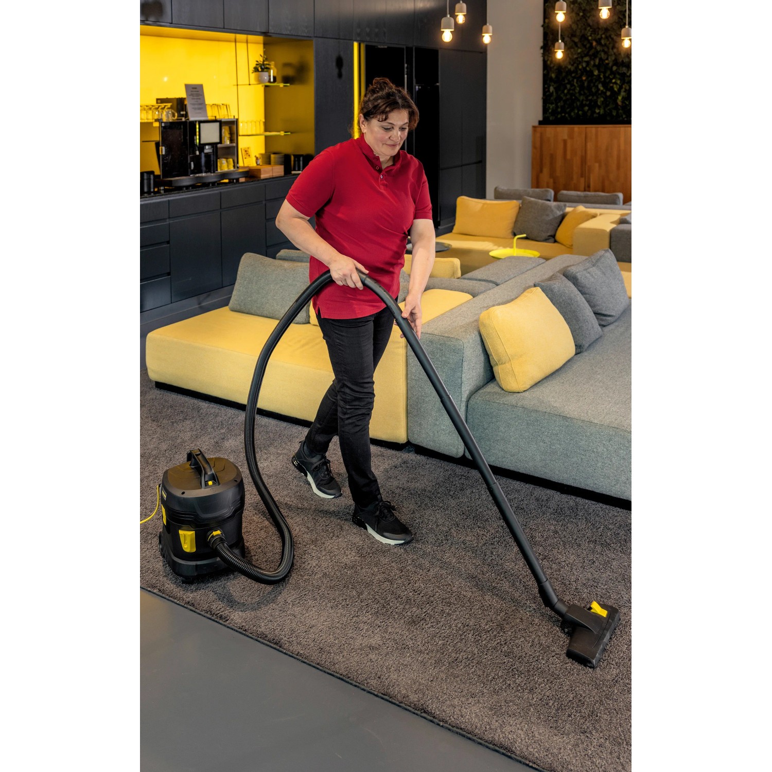 Frau saugt mit Kärcher T 11/1 Classic Adv Trockensauger Teppich. Kompakter, leiser Gewerbesauger.