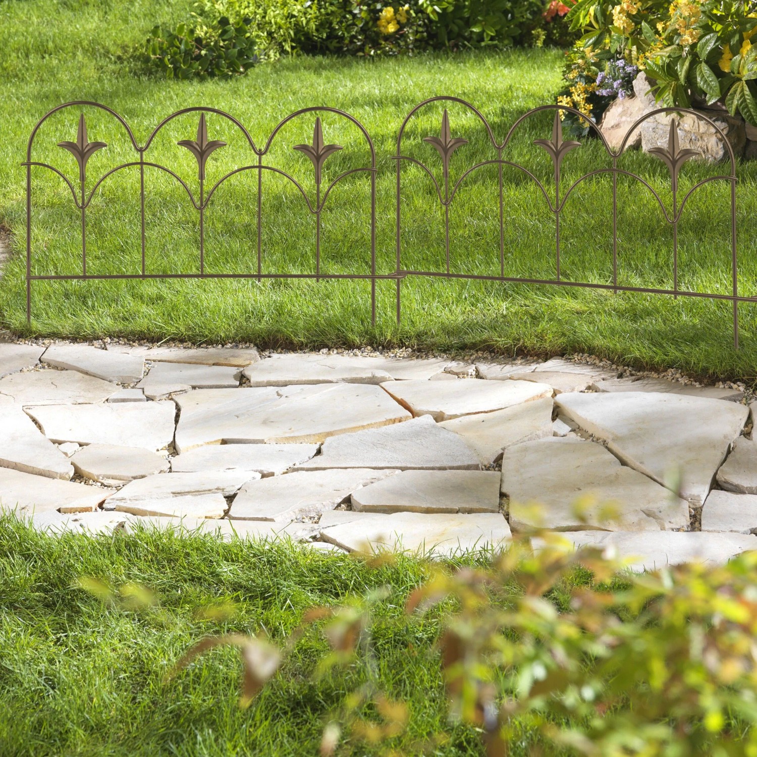 Bronzene Beeteinfassung aus Stahl mit Fleur-de-Lis-Ornamenten trennt Rasen von Steinweg im Garten. 4er Set.