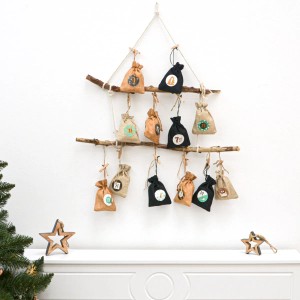 DIY Adventskalender mit 24 braunen Jute-Säckchen zum Selbstbefüllen an einem Ast aufgehängt.