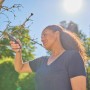 Frau schneidet mit Gardena Gartenschere PremiumCut einen Ast im Garten.