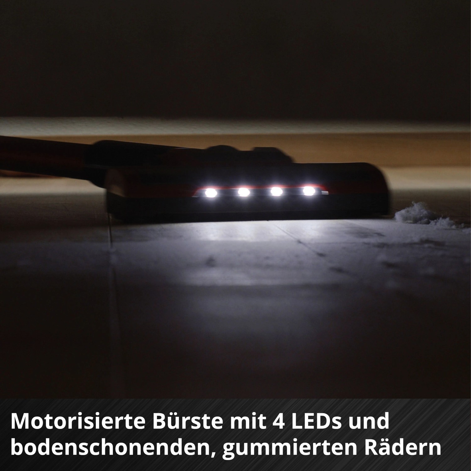 Motorisierte Bodendüse des Einhell Akku-Stielstaubsaugers mit 4 LEDs beleuchtet Staub auf dunklem Boden für gründliche Reinigung.