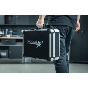 Person trägt robusten schwarzen Aluminium Werkzeugkoffer mit Woodster Logo in Werkstatt. Ideal für Transport.