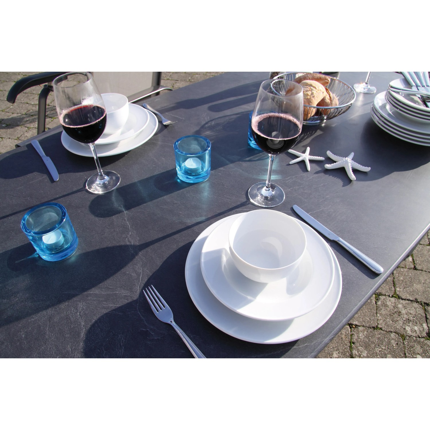 Gedeckter Acamp Gartentisch Acaplan Loft mit Urban Klappsesseln und Geschirr.