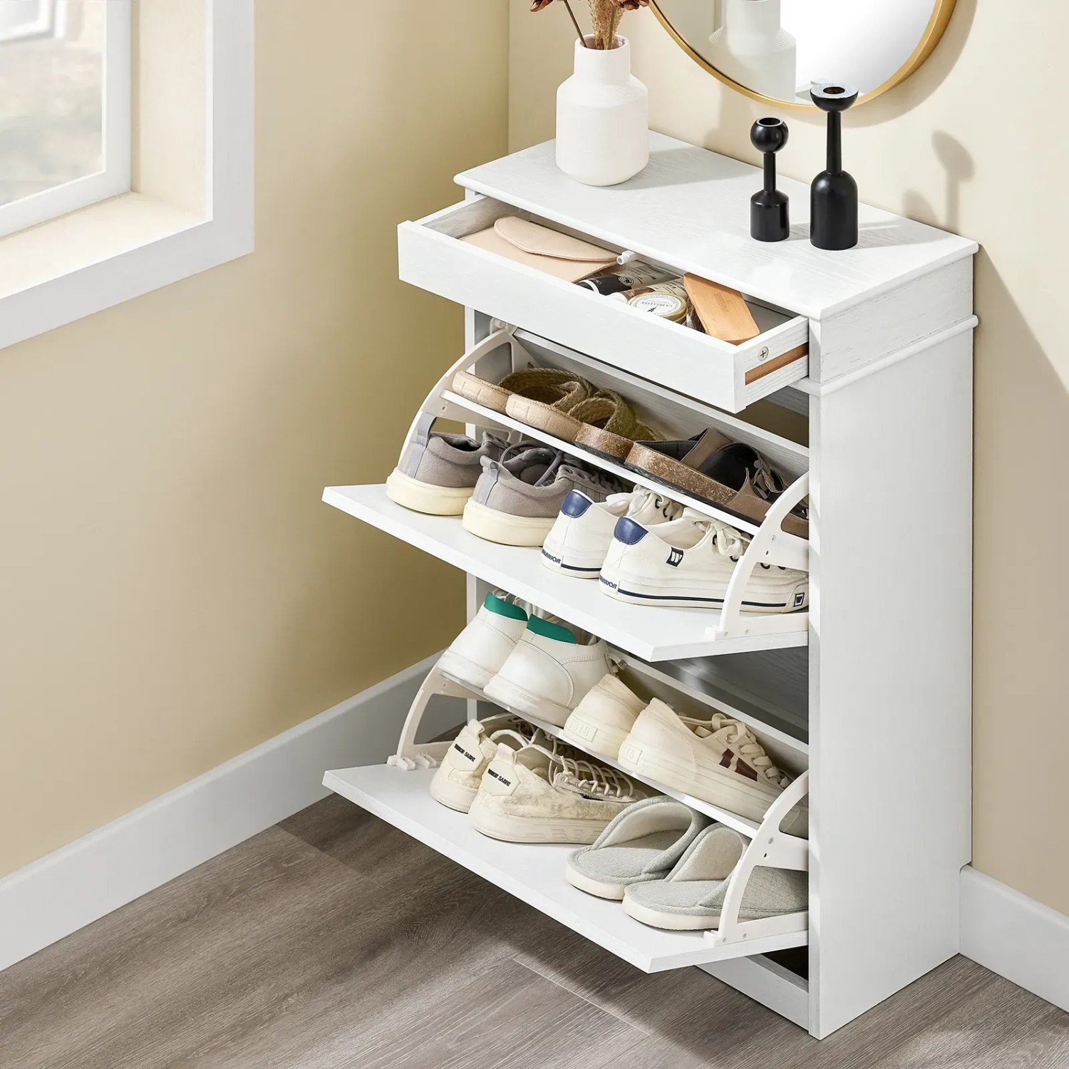 Weißer, schmaler Schuhschrank mit 2 Klappen und Schublade, gefüllt mit Schuhen und Kleinigkeiten, im Flur.
