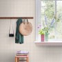 ESTAhome Vliestapete mit beigem Karomuster an einer Wand, dekoriert mit Garderobe und Fenster.