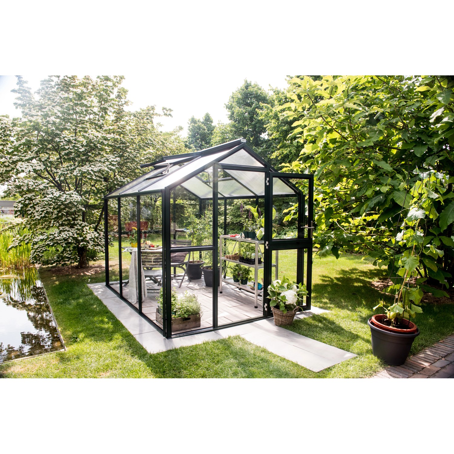 KGT Gewächshaus Galant III, tannengrün, 6,65 m² im Garten mit Pflanzen.