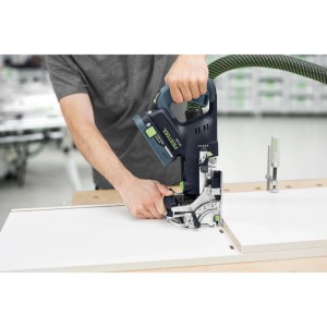 Person nutzt Festool Akku-Dübelfräse DFC 500 E auf weißem Holzbrett. Grüner Absaugschlauch, 18V Akku für präzise Holzverbindungen.