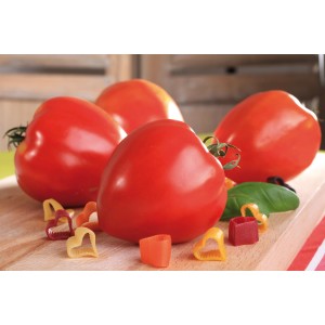 Veredelte Ochsenherztomaten (Solanum lycopersicum) auf Holzbrett mit herzförmiger Pasta.