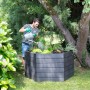 Garantia Hochbeet Ergo XL 75 Wood: Mann gießt Pflanzen im grauen Kunststoff-Hochbeet im Garten.
