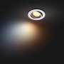Weißer, runder Philips Hue LED-Einbauspot Milliskin mit warmweißem Licht an dunkler Decke.