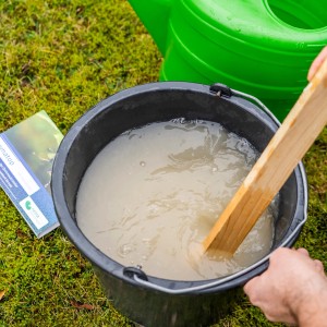 Anmischen von e-nema Nematoden gegen Dickmaulrüssler in einem Eimer mit Wasser.