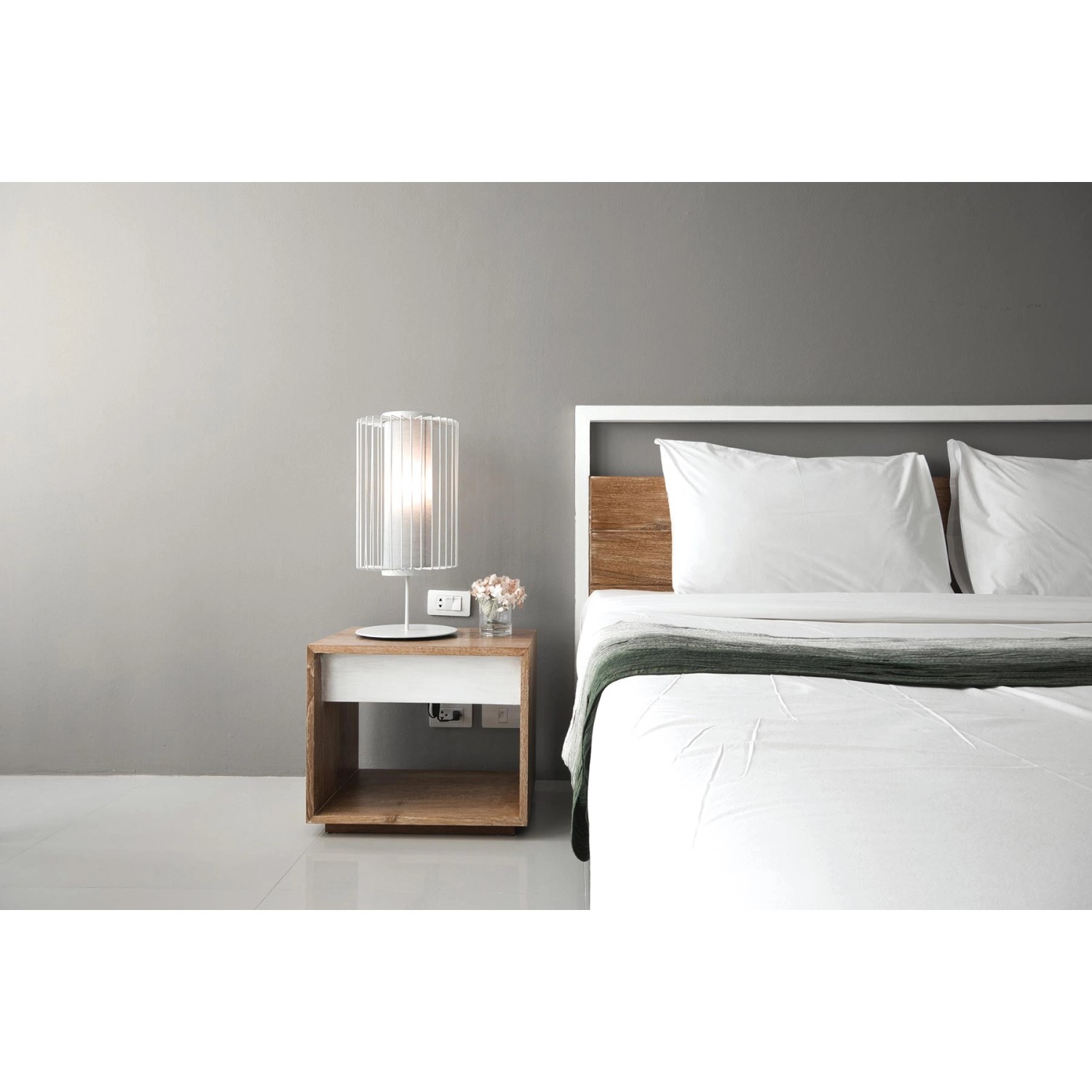 Graue Tadessi Unitapete an Wand hinter Bett mit Nachttisch und Lampe.