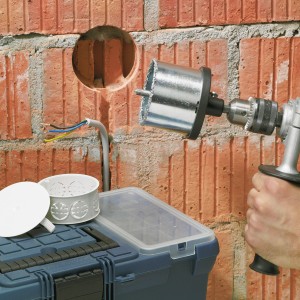 LUX HM-Bohrkrone 83 mm im Einsatz an einer Ziegelwand, Bohrmaschine und Werkzeugkoffer im Bild.