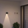 Schwarze Philips Hue Resonate LED-Außenwandleuchte mit Lichtkegel an Hauswand.