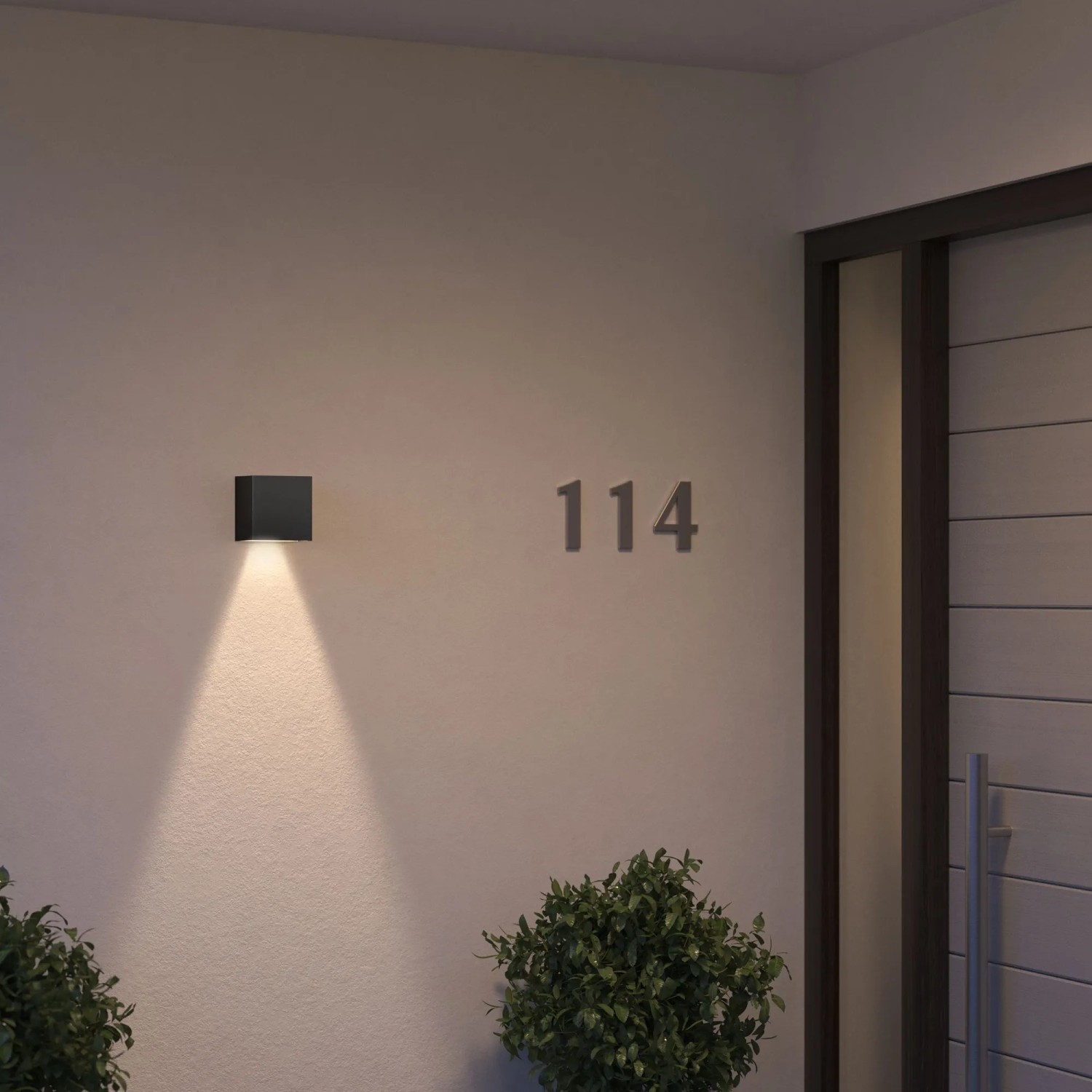 Schwarze Philips Hue Resonate LED-Außenwandleuchte mit Lichtkegel an Hauswand.