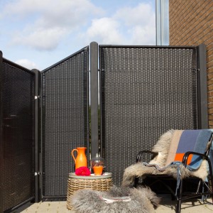 Schwarzer Sichtschutzzaun aus Polyrattan, 115x140 cm, mit Deko-Elementen im Garten.