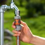 Hand verbindet orange-graues Gardena Schlauchstück 19 mm (3/4) mit Wasserhahn und Gartenschlauch.