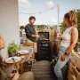 Enders Urban II Gasgrill mit Trolley auf Balkon mit grillenden Personen.