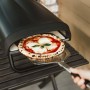 Enders Pizzaofen Paco mit Pizza auf Pizzaschieber vor dem Ofen.