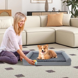 Graues orthopädisches Hundebett, groß, mit Corgi-Welpe und spielender Frau. Bequemes Hundesofa für Haustiere.