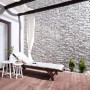 Stegu Verblender Nepal Beige-Grau an Wand hinter Liege und Tisch auf Terrasse.