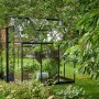Schwarzes Halls Gewächshaus Qube 66 mit Pflanzen im Garten.