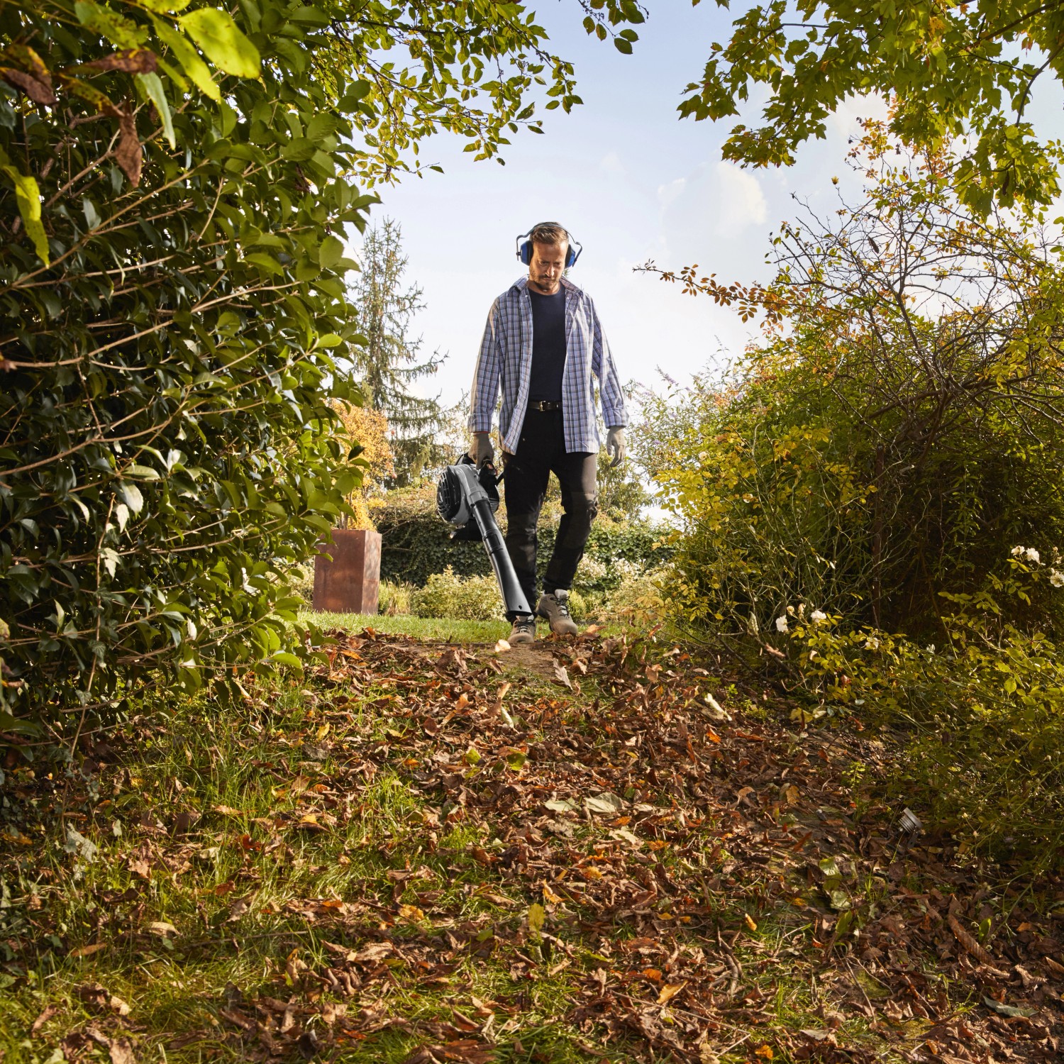 Mann nutzt Alpina Benzin-Laubbläser ABL 27 V im Garten. Laubbläser mit Saugfunktion.