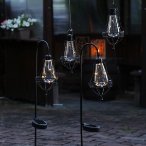 4 schwarze LED Solar Laternen aus Metall, 2 hängend, 2 mit Erdspieß, leuchten dekorativ im Garten.