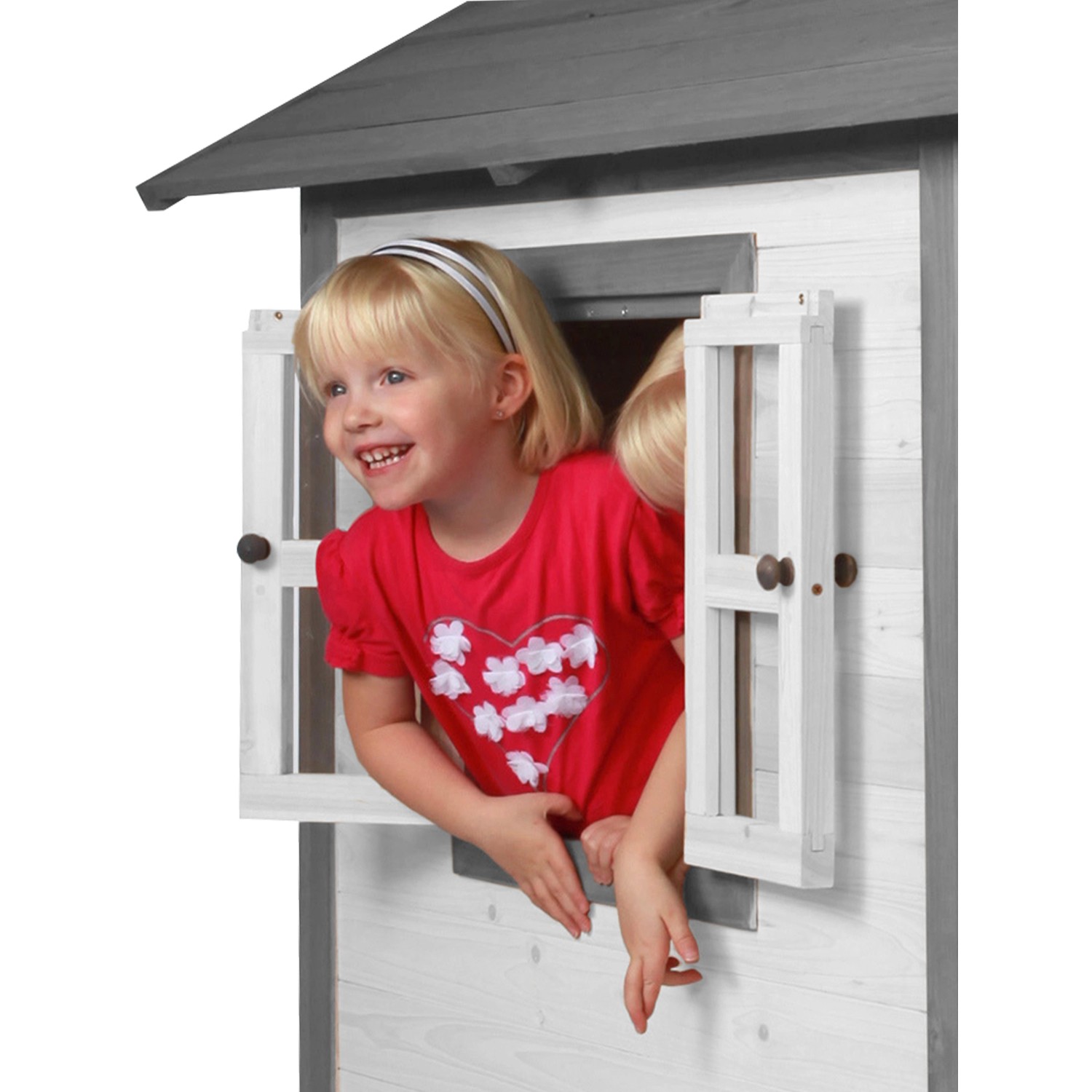 Fröhliches Mädchen schaut aus dem Fenster des grauen Axi Lodge Spielhauses aus Holz.