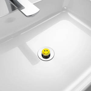 Sanilo Pop Up Waschbeckenstöpsel mit Smiley-Motiv im weißen Waschbecken.